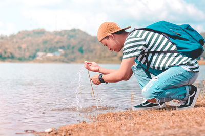 Side view of man holding water in lake