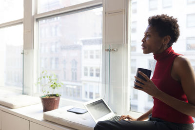 Side view of young man using mobile phone at home