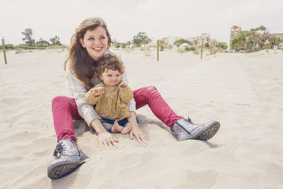 Portrait of happy girl sitting on sand at beach