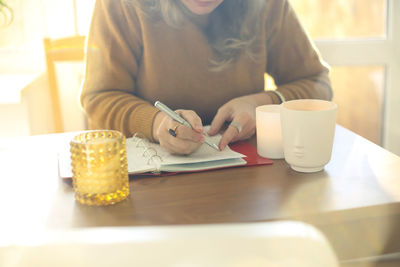 Midsection of woman using mobile phone on table