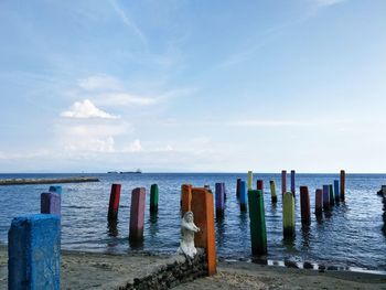 Colorful posts on beach against sky