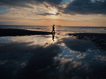 Silhouette man on beach against sky during sunset