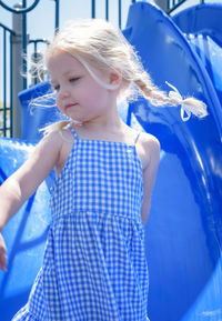 Cute girl standing against blue slide in park