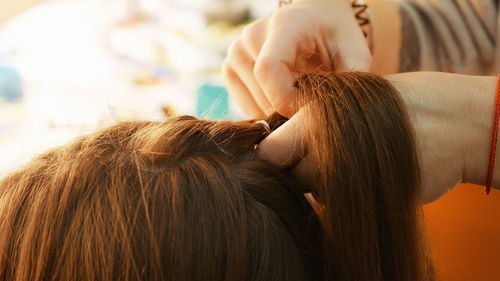 Cropped hands of female hairstylist styling girl hair