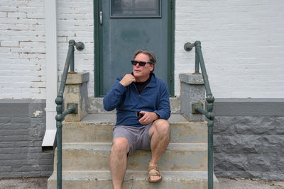 Man in sunglasses sitting against house