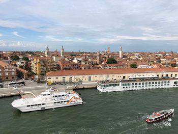 Nautical vessel on river by buildings in city against sky