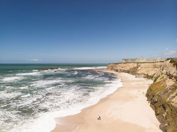 Scenic view of beach against clear blue sky