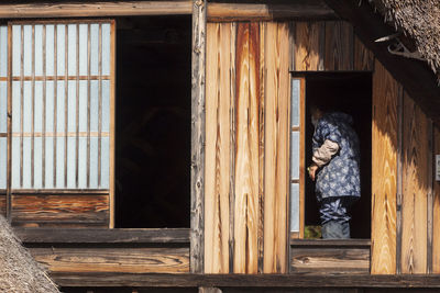 Woman looking through window of house