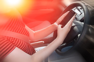Midsection of woman using mobile phone in car