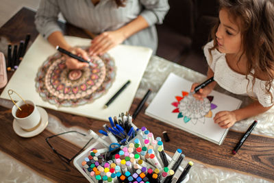 Mother and daughter drawing while sitting at home