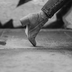 Low section of woman walking on street, leather shoe with heels