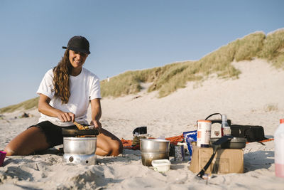 Smiling woman cooking on beach