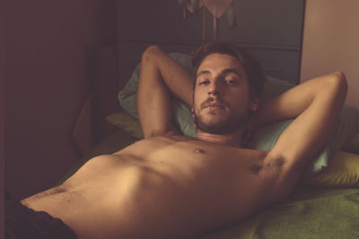 Portrait of shirtless man lying in bed