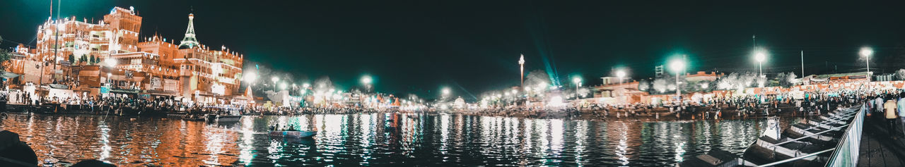 Panoramic view of illuminated buildings by river at night