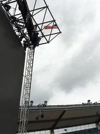 Low angle view of crane against cloudy sky