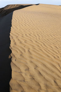 Scenic view of sand dunes at beach against sky