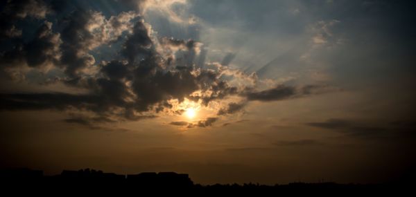 Silhouette landscape against dramatic sky during sunset