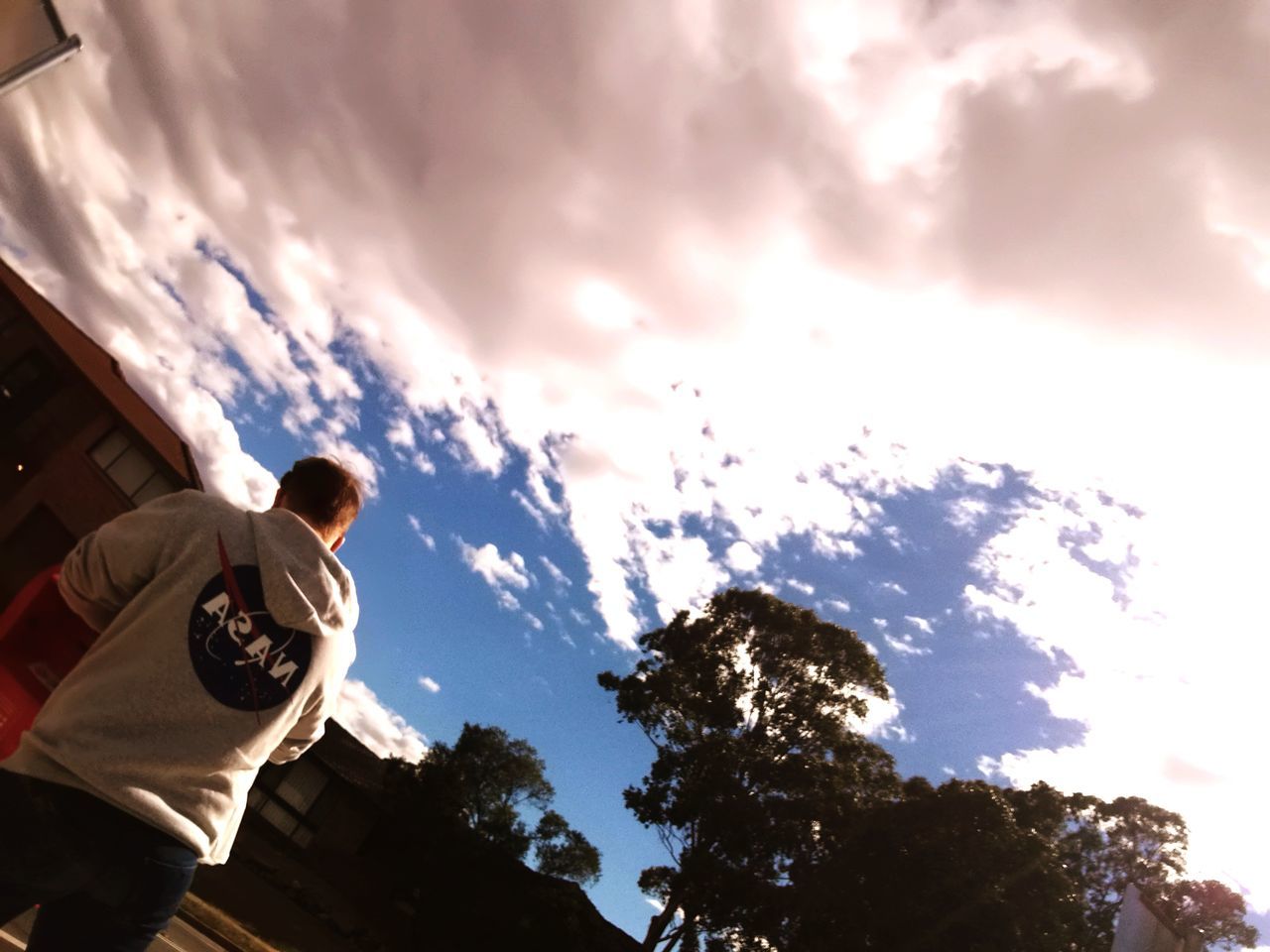 cloud - sky, sky, low angle view, nature, tree, real people, men, one person, lifestyles, leisure activity, plant, outdoors, day, architecture, sunlight, casual clothing, standing, child, built structure, teenager