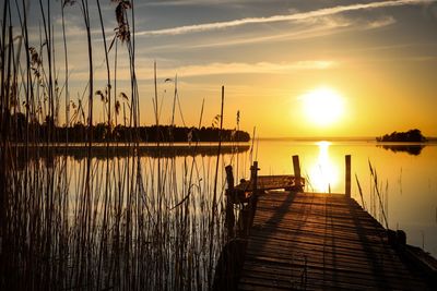 Pier over lake against sky during sunset