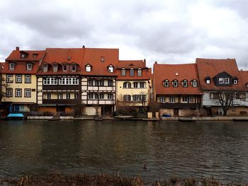 Residential buildings by river against sky