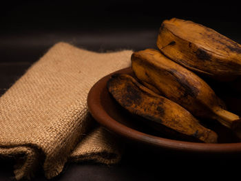 Stack of boiled bananas on a round pottery plate. shoot on a black background