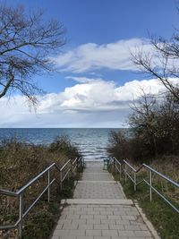 Footpath by sea against sky