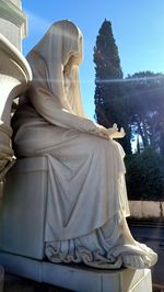 Statue of woman sitting against sky