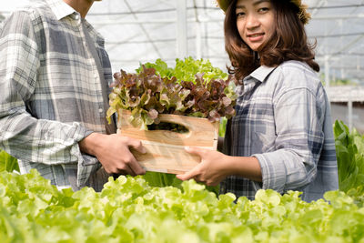 Portrait of smiling young couple holding flower at store