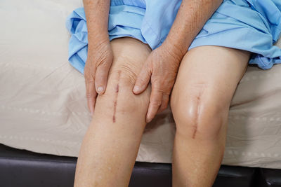 Midsection of man and woman sitting on bed