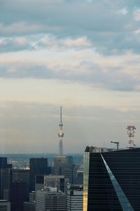 Communications tower in city against sky during sunset