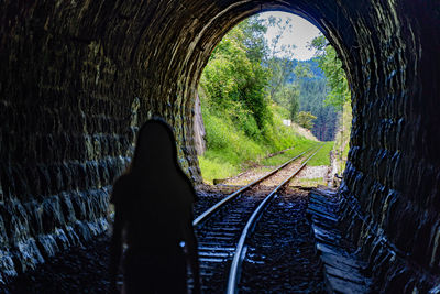 Rear view of man on railroad track in tunnel
