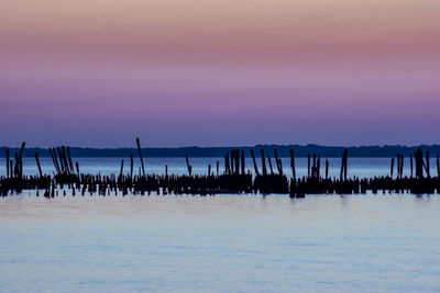 Silhouette wooden post in seascape during sunset