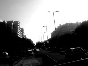 Cars on city street against clear sky