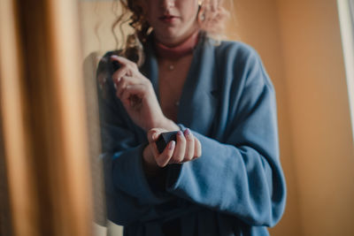 Midsection of young woman reflecting on mirror at home