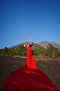 Woman with red umbrella against clear sky