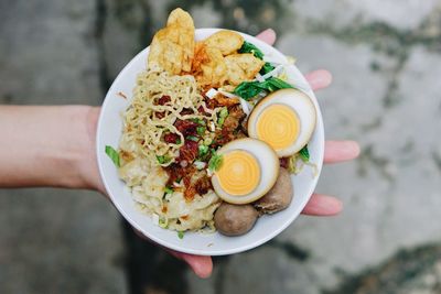 Cropped hand of person holding food in plate