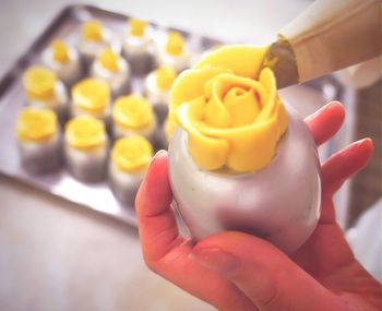 Cropped image of hands making rose with whipped cream at home