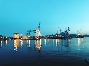 Cranes at commercial dock against clear sky