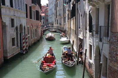 High angle view of people on gondolas at canal amidst buildings