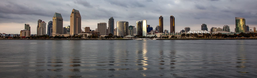 Sea by modern buildings against sky in city