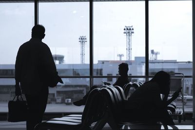 Rear view of silhouette people standing at airport