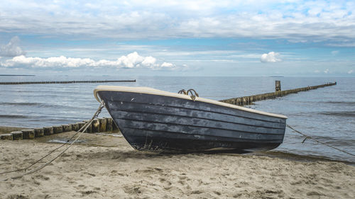 Moored boat on beach against sky