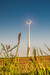 Wind turbine in motion on field against clear blue sky