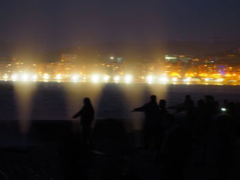 Silhouette people at illuminated city at night