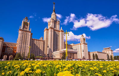 Spring campus of moscow university with yellow dandelion field under sunny blue sky