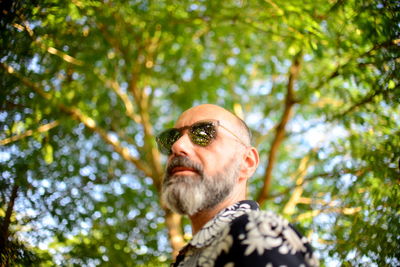 Low angle view of man wearing sunglasses against trees in forest