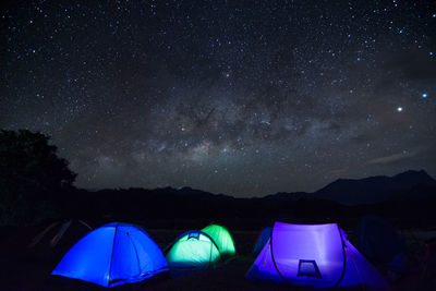 Illuminated tents on mountain against sky at night