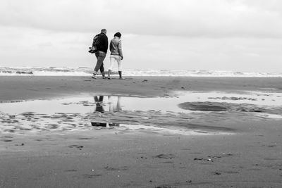 Rear view of people walking on beach