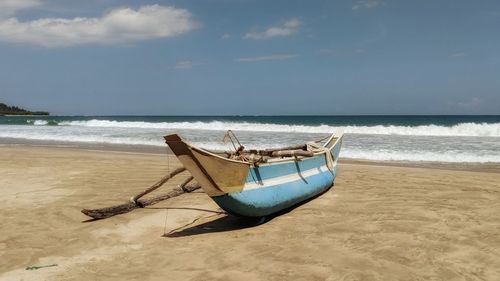 Boat moored on beach against sky