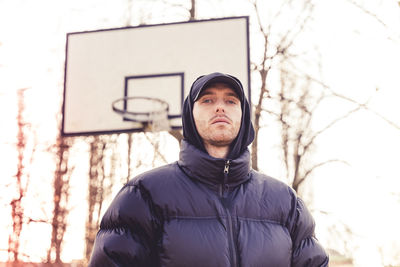 Portrait of young man standing against basketball